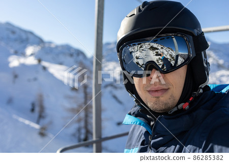 ski resort man on chairlift in helmet and mask 86285382