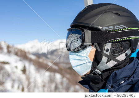 ski resort man on chairlift in helmet and medical mask 86285405