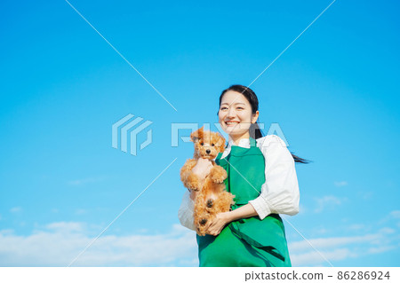 女性和她的狗玩耍(看著相機) 女性和她的狗玩耍(看著相機) 86286924