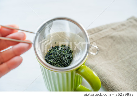 綠茶放入帶有濾茶器的杯子中 86289982