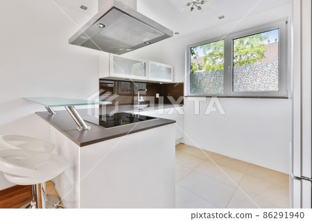 A fascinating kitchen with a mirrored black countertop and beige tiled floor A fascinating kitchen with a mirrored black countertop and beige tiled floor 86291940