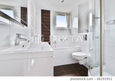 A fascinating bathroom with dark brown tiles and a bathtub with a window A fascinating bathroom with dark brown tiles and a bathtub with a window 86291952