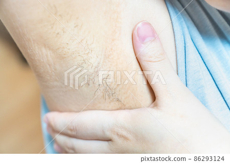 20多歲女人腋毛的照片。廢棄頭髮、美容和護理的形象。 20多歲女人腋毛的照片。廢棄頭髮、美容和護理的形象。 86293124