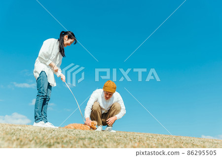 Men and women playing with their dog Men and women playing with their dog 86295505