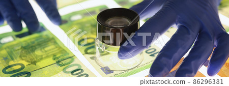 Expert with gloves checks authenticity of euro banknotes Expert with gloves checks authenticity of euro banknotes 86296381