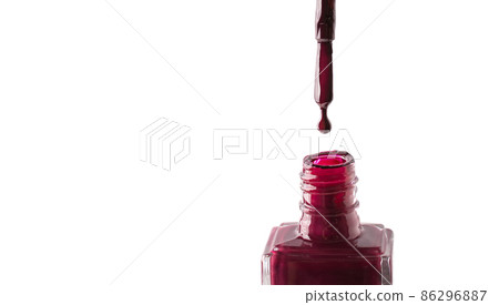 Red nail polish drop dripping from a brush into a bottle isolated on white background. 86296887