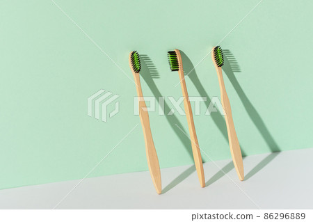 Eco friendly bamboo toothbrushes over green wall. Zero waste hygiene products concept. 86296889