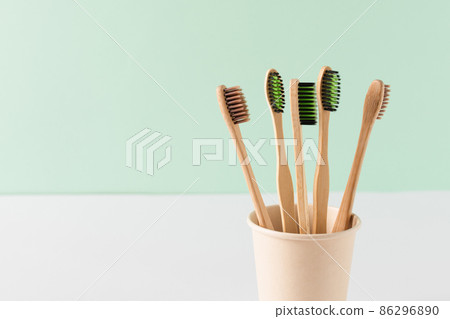 Eco friendly bamboo toothbrushes over green wall. Zero waste hygiene products concept. 86296890
