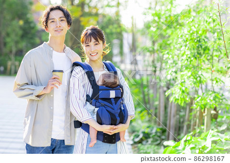 A couple walking outside while holding a baby 86298167