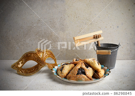 Jewish holiday Purim background with hamantaschen or hamans ears cookies, carnival mask and noisemaker 86298845