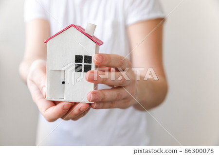 Woman hand holding toy model house isolated on white background. Real estate mortgage property insurance dream home concept. Offer of purchase rental house, family life, business real estate Woman hand holding toy model house isolated on white background. Real estate mortgage property insurance dream home concept. Offer of purchase rental house, family life, business real estate 86300078