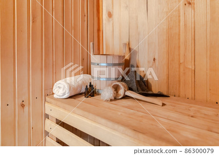 Traditional old Russian bathhouse SPA Concept. Interior details Finnish sauna steam room with traditional sauna accessories set basin towel aroma oil scoop felt. Relax country village bath concept Traditional old Russian bathhouse SPA Concept. Interior details Finnish sauna steam room with traditional sauna accessories set basin towel aroma oil scoop felt. Relax country village bath concept 86300079