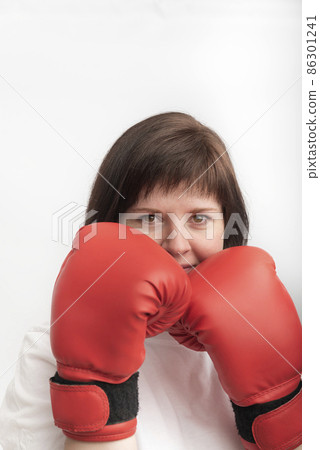 Portrait of young dark-haired woman in red boxing gloves. Woman boxer on white background. Vertical frame 86301241
