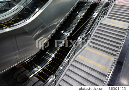 Electric escalators and normal staircases in subway station. Easy and convenient walkway in community mall, shopping center, plaza, airport terminal, or metro. 86301423