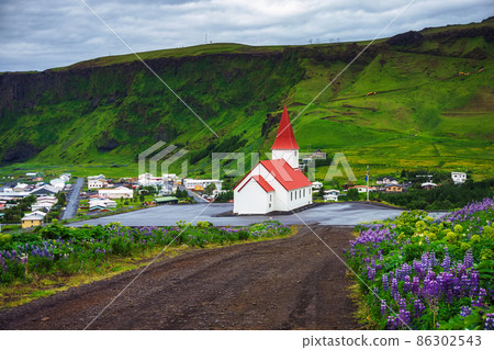 Dirt road going to the village of Vik and its church in Iceland Dirt road going to the village of Vik and its church in Iceland 86302543