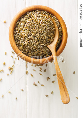 Raw freekeh or firik, roasted wheat grain in bowl on white table. Vertical top view Raw freekeh or firik, roasted wheat grain in bowl on white table. Vertical top view 86303139
