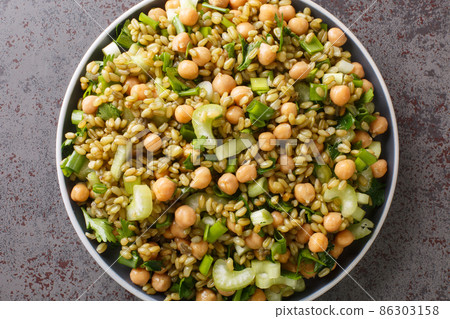 Fresh vegan freekeh salad with chickpeas, celery and herbs close-up in a plate. horizontal top view 86303158