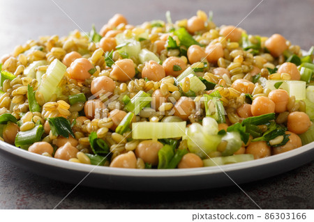 Fresh vegan freekeh salad with chickpeas, celery and herbs close-up in a plate. horizontal 86303166