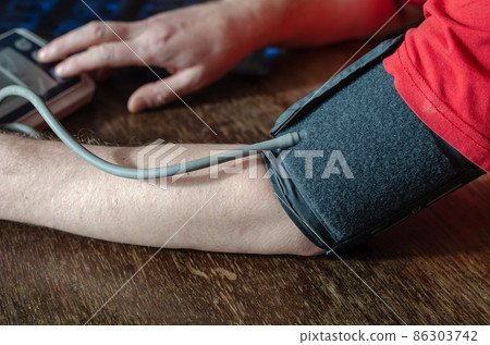 Close-up of a man's shoulder with a blood pressure cuff on. Close-up of a man's shoulder with a blood pressure cuff on. 86303742