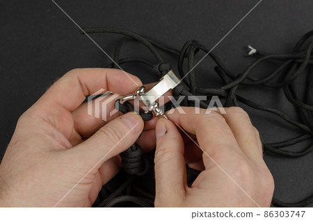 Two male hands clasping a braided paracord. 86303747