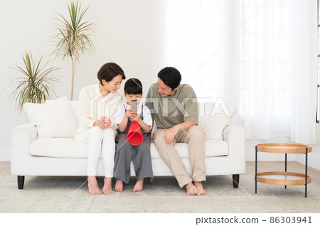 一家三口父母和孩子在電視上看體育節目 86303941