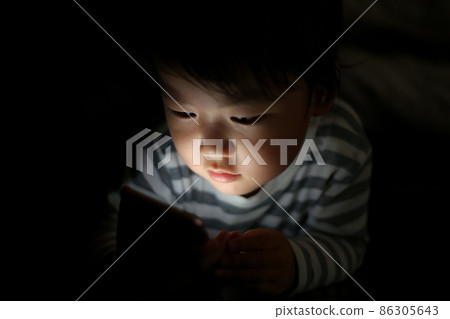 Boy using a smartphone in the dark 86305643