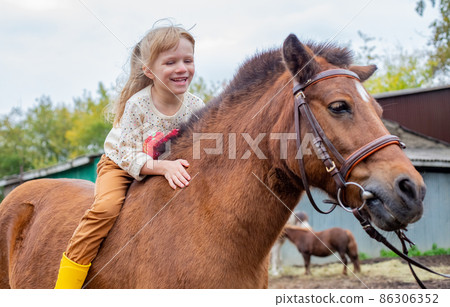 happy little girl riding pony horse bareback and laugh 86306352
