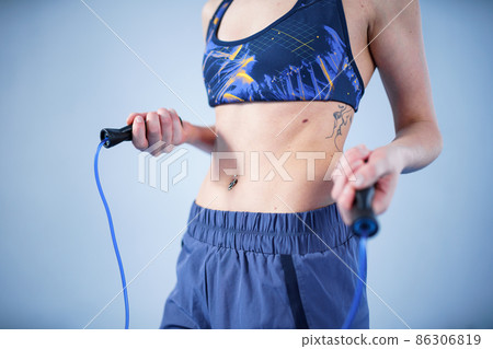 Smiling sportswoman posing with a skipping rope. Female with muscular body posing with jump rope. Fitness model. Body positivity, sport, fitness concept. Healthy lifestyle. Fit woman with jump rope 86306819