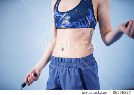 Fit woman with jump rope posing in the gym. Sport exercises healthy lifestyle concept. Sporty happy woman with skipping rope posing to the camera. Active lifestyle concept. Healthy lifestyle 86306827