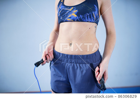 Smiling sportswoman posing with a skipping rope. Female with muscular body posing with jump rope. Fitness model. Body positivity, sport, fitness concept. Healthy lifestyle. Fit woman with jump rope 86306829
