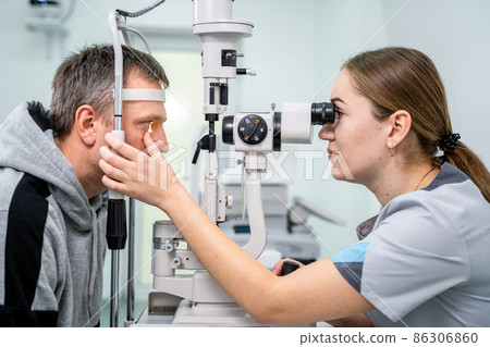 Doctor and patient in ophthalmology clinic. Male patient checking vision with special eye equipment. Optometry concept. Man visiting optician. Patient at slit lamp of optician or optometrist 86306860