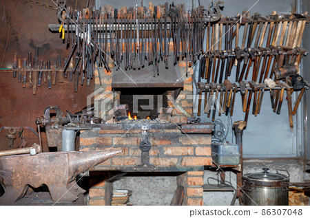 Metal anvil in a blacksmith shop and various tools in blur. 86307048