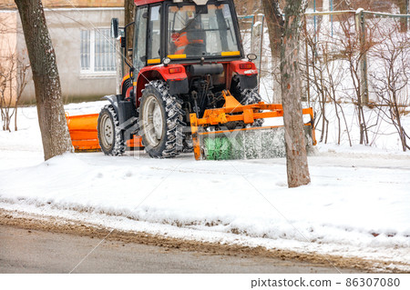 Road compact tractor cleaner cleans snow on the sidewalk. 86307080