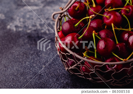 Fresh sweet red cherries in the basket on dark background Fresh sweet red cherries in the basket on dark background 86308538