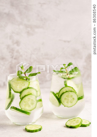 Fresh infused cucumber water on a light background Fresh infused cucumber water on a light background 86308540