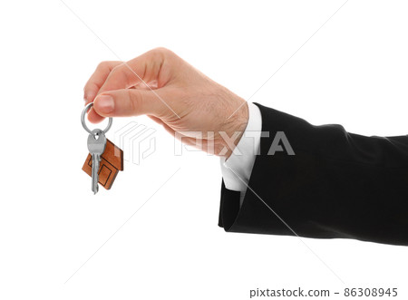 Real estate agent holding house key with trinket on white background, closeup 86308945