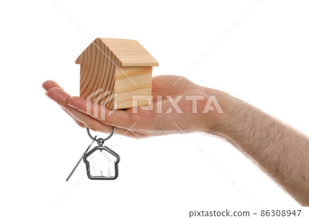 Real estate agent holding house figure and key on white background, closeup 86308947