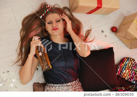 Young woman suffering from hangover in messy room after New Year party, above view Young woman suffering from hangover in messy room after New Year party, above view 86309030
