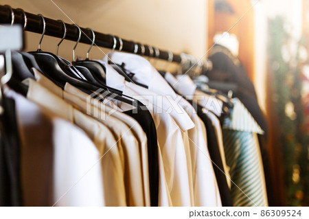 Clothes hang on a shelf in clothes store. Clothes for women hanging on hangers in home closet or shopping mall for store sale concept. 86309524