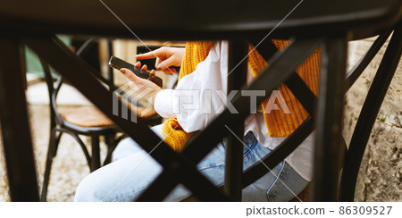 Close up of woman's hands in sweater holding and using mobile smartphone. Close up of woman's hands in sweater holding and using mobile smartphone. 86309527