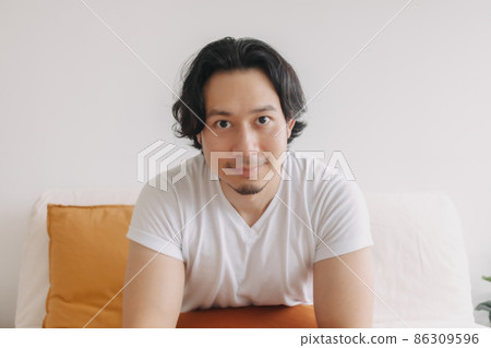 Happy smile face long hair man sit and relax on the sofa in living room. Happy smile face long hair man sit and relax on the sofa in living room. 86309596