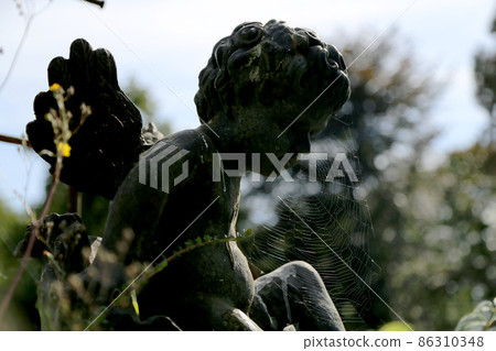 Beautiful Cupid angel statue with wings on back in vintage garden 86310348