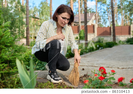 Woman sweeping with a broom in the yard 86310413