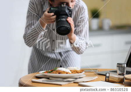 Food blogger taking photo of her lunch at table Food blogger taking photo of her lunch at table 86310528