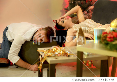 Drunk couple sleeping in messy room after New Year party 86310776
