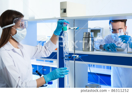 Scientist pouring liquid through glass distillation condenser indoors. Laboratory analysis 86311252