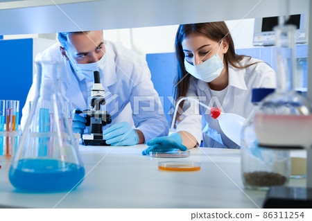 Scientists doing research and analysis with microscope in laboratory Scientists doing research and analysis with microscope in laboratory 86311254