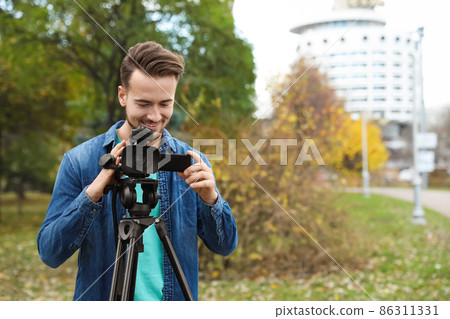 Video operator with camera working in park. Space for text 86311331