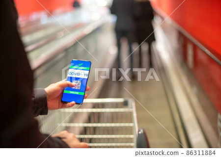 Man with covid certificate on smartphone  which allows him to buy goods 86311884