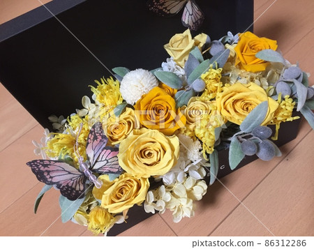 A yellow-based preserved flower in a black box that I received as a gift 86312286